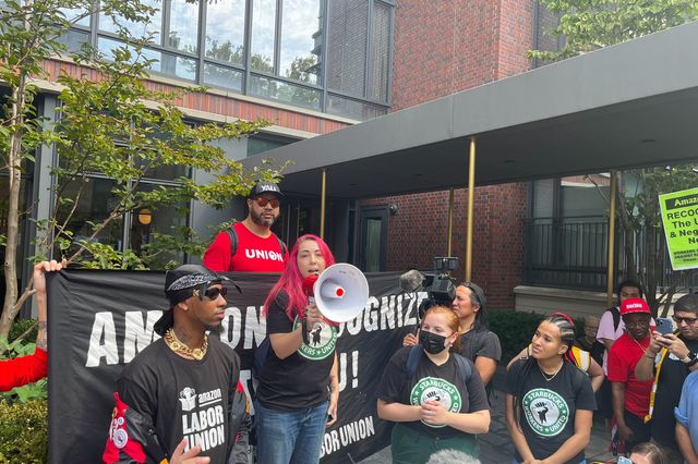 Starbucks employee Megan DiMotta holds a megaphone as she speaks outside interim CEO Howard Schultz’s residence in Greenwich Village during a protest on Labor Day. She is flanked by Amazon Labor Union President Chris Smalls (left) and other current and former Starbucks workers.